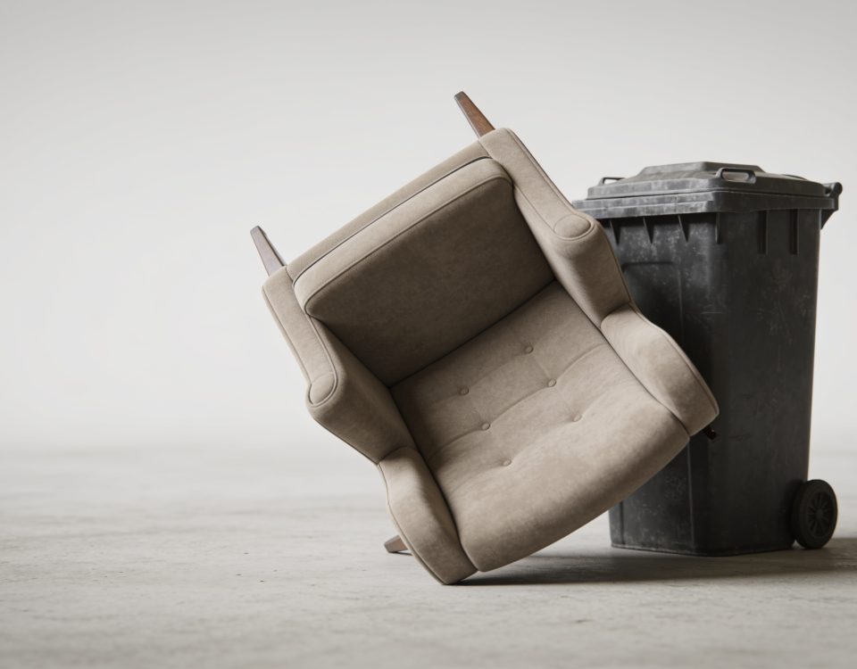 Fauteuil renversé posé contre un conteneur de dechets