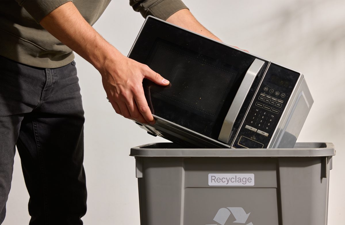 Personne deposant un four a microondes dans un bac recyclage