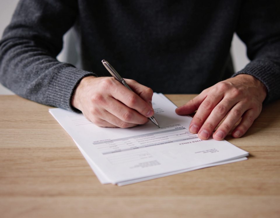 Personne seule signant des documents financiers à table.