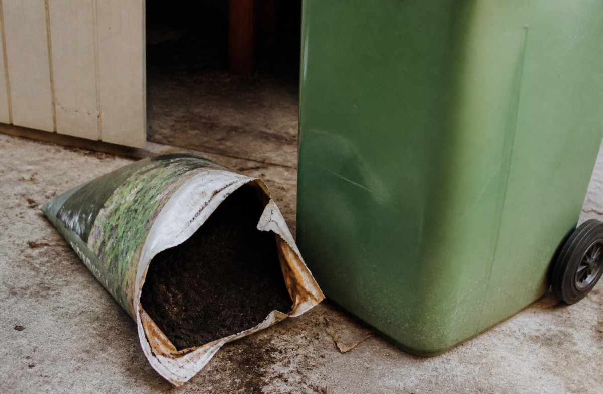 Sac de terreau ouvert pres d'une poubelle verte