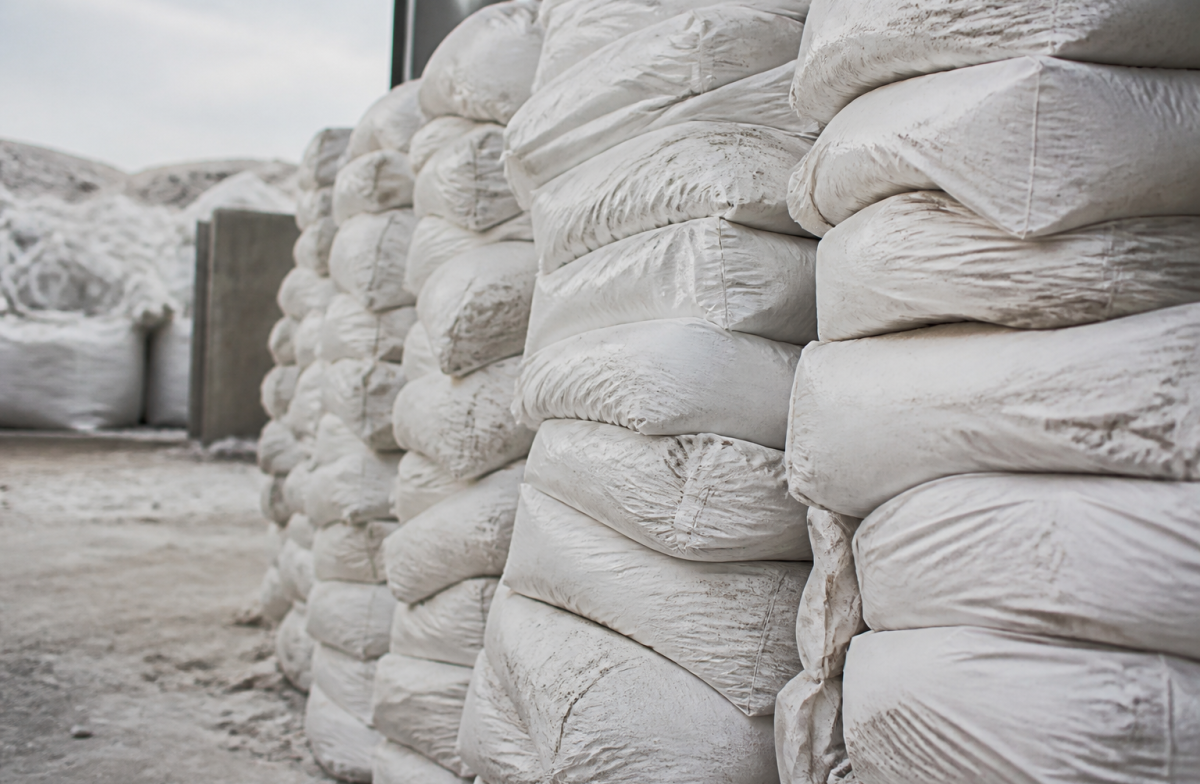 Sacs blancs de plâtre empilés verticalement dans un centre de recyclage.