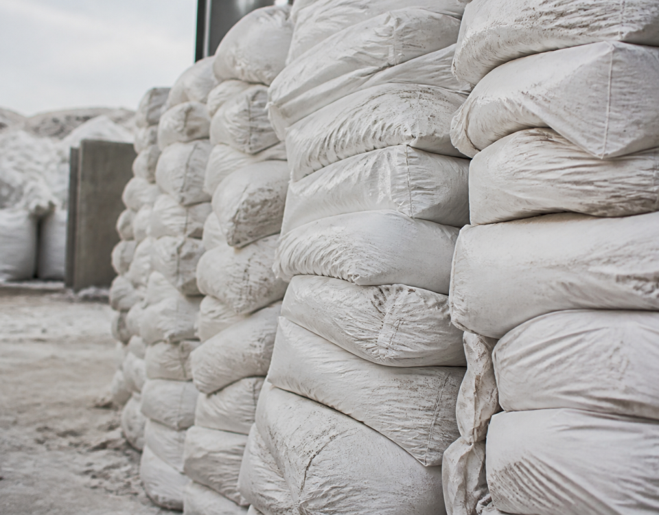 Sacs blancs de plâtre empilés verticalement dans un centre de recyclage.