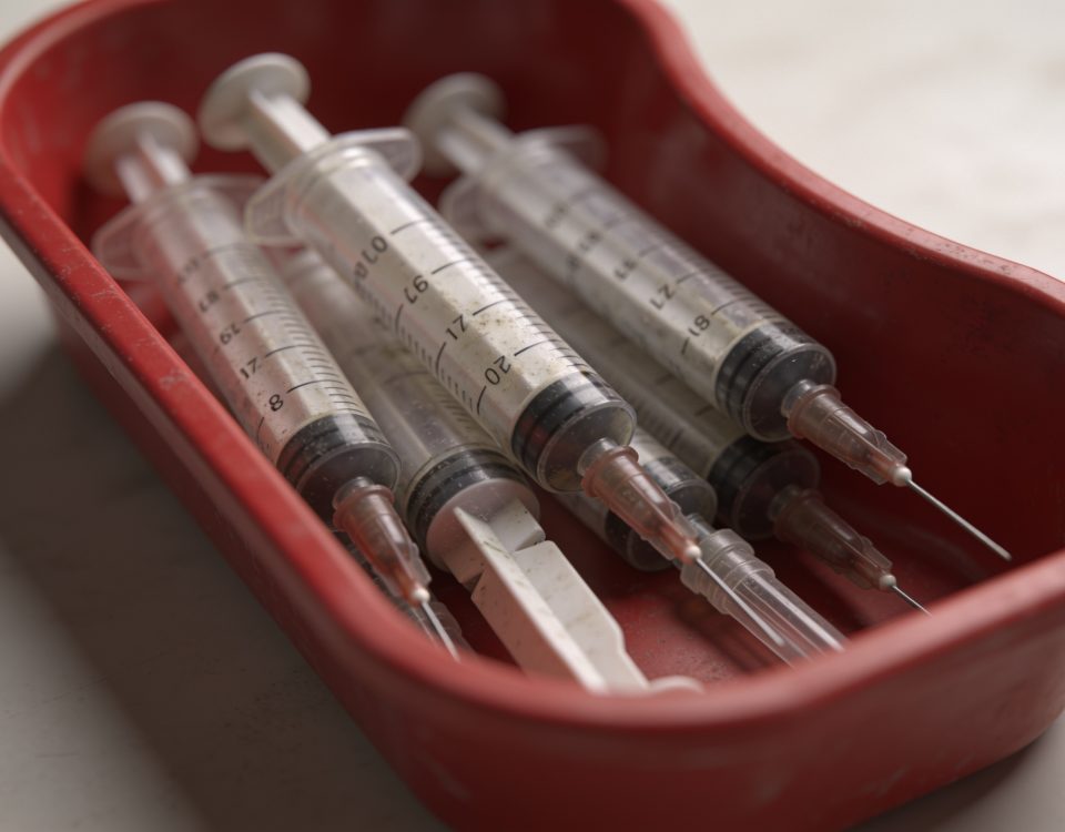 Seringues usagees placees dans un conteneur medical rouge
