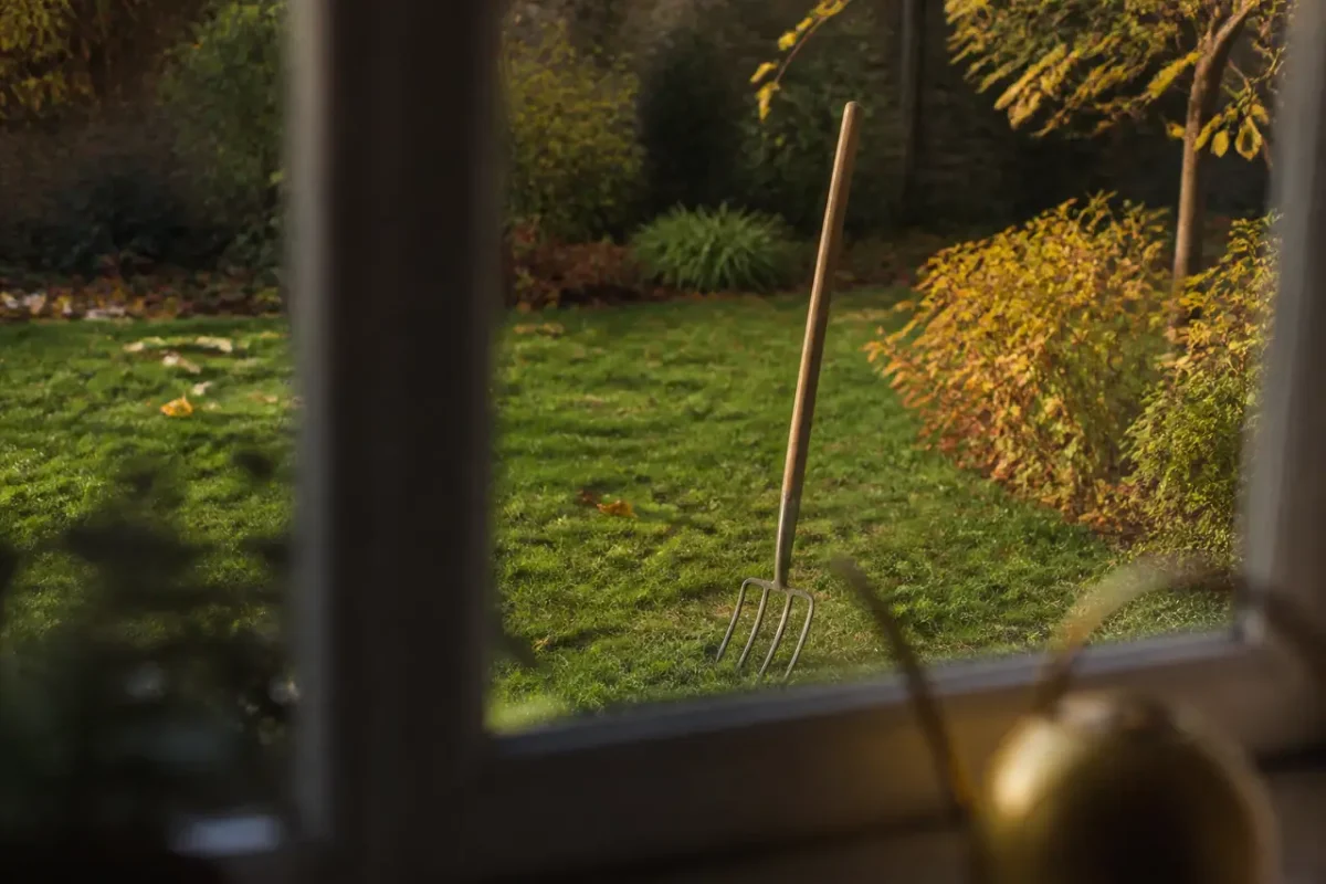 Jardinier enfonce une fourche dans la pelouse automnale