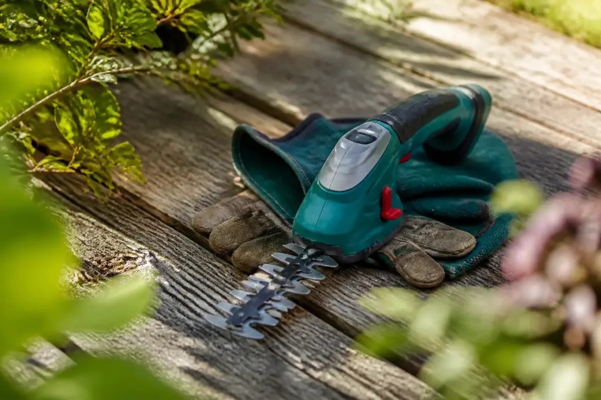 Jardinier en gants manie une cisaille electrique au jardin