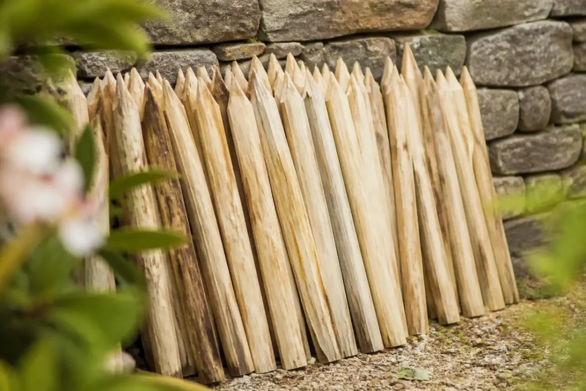 Piquets fendus en bois clair contre un muret